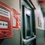 Déclenchement manuel incendie : déclencheur NF rouge près porte de secours